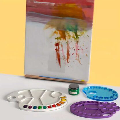 Paletas mezcladoras de pintura sobre la meza con un lienzo de fondo con pintura de colores